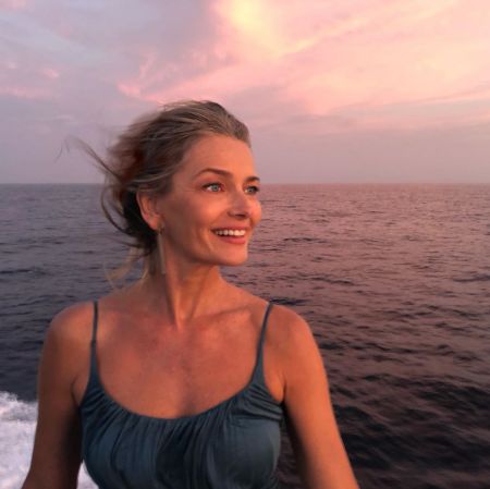 Paulina Porizkova in a blue top poses at a yacht at the middle of a ocean.
